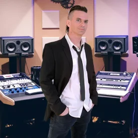 Wouter Baustein in suit in front of studio speakers and console